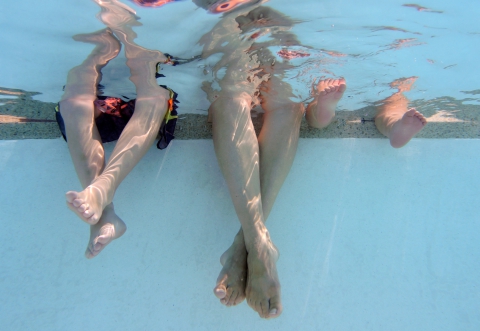 Family of three enjoying their toes dipped in the backyard swimming pool.