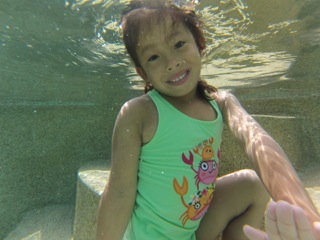 Child holding her breathe and opening her eyes under water during swimming lessons.