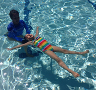 Child practicing back floats during swimming lessons.