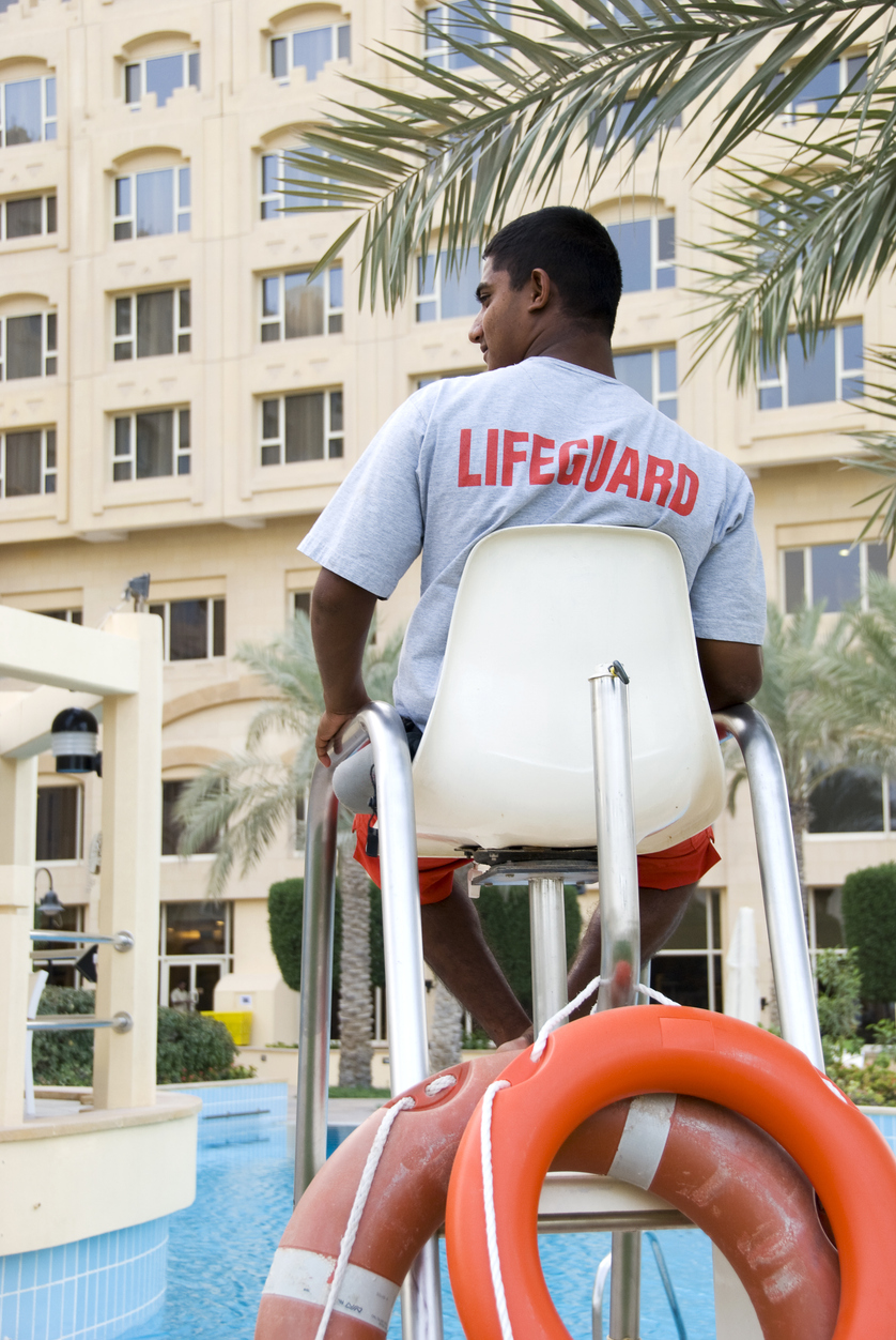 Lifeguard on Duty looking out over swimming pool reviewing the RID Factors. Swan Aquatics has Lifeguards for Hire and American Red Cross Lifeguard Instructor Courses